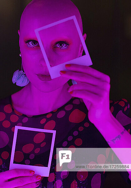Porträt stilvolle Frau mit rasiertem Kopf hält Polaroid über Auge