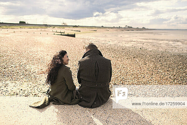 Couple in winter coats on sunny beach