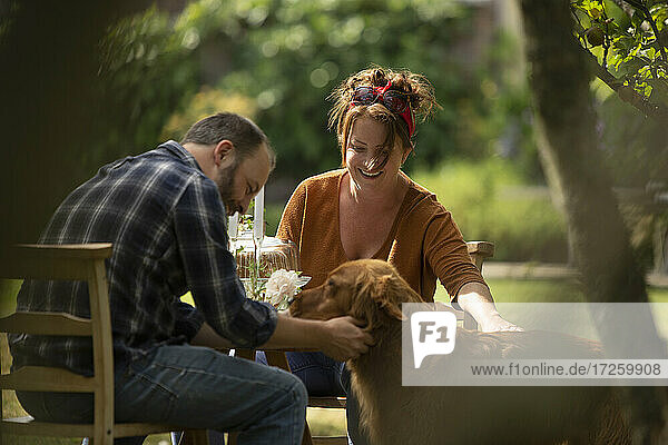 Glückliches Paar mit Golden Retriever Hund am Gartentisch