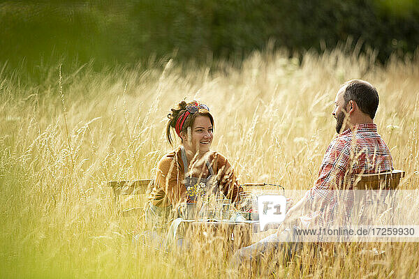 Glückliches Paar entspannt am Tisch im sonnigen hohen Gras