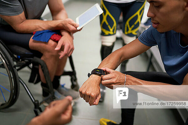 Male amputee and wheelchair athletes with smart phone in locker room