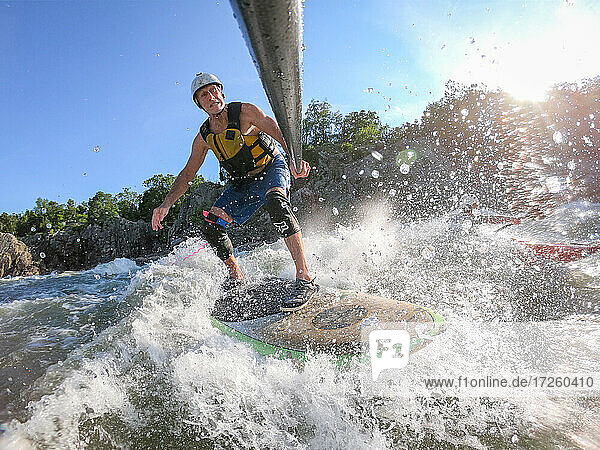 Der Fotograf Skip Brown surft mit dem Stand Up Paddle auf dem anspruchsvollen Wildwasser unterhalb der Great Falls des Potomac River  Grenze zwischen Virginia und Maryland  Vereinigte Staaten von Amerika  Nordamerika