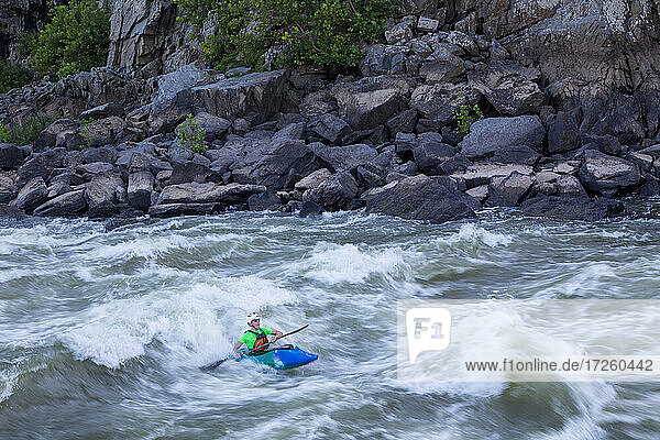 A kayaker surfs big standing waves of the Potomac River near Great Falls in his whitewater boat  Virginia  United States of America  North America