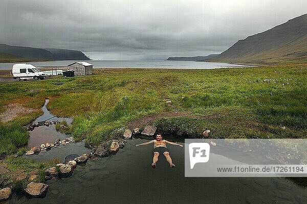 Natural pool at fjord  hot pot  geothermal spring  man bathing Reykjafjarðarlaug  Vestfirðir  Westfjords  Iceland  Europe