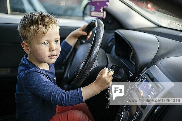 Small boy having fun by steering wheel in the car