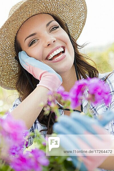 Attraktive glückliche junge erwachsene Frau mit Hut bei der Gartenarbeit im Freien
