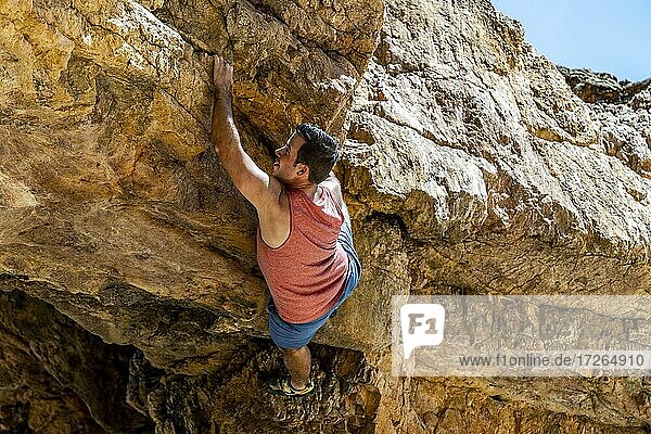 Young rock climber safely climbing a yellow cliff in Algarve  Portugal  Europe
