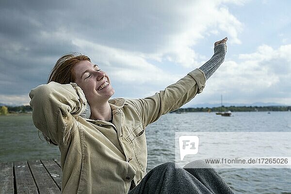 Junge Frau streckt sich glücklich  am See  Starnberger See  Oberbayern  Bayern  Deutschland  Europa