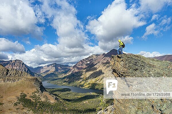 Hiker standing on rock ledge  view of Two Medicine Lake  mountain peaks Rising Wolf Mountain and Sinopah Mountain  hiking trail to Scenic Point  Glacier National Park  Montana  USA  North America
