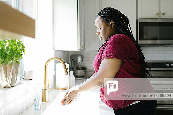 Frau wäscht Hände in der Küchenspüle