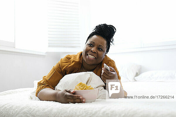 Frau isst Kartoffelchips im Bett