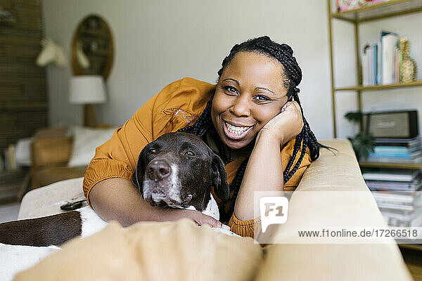 Smiling woman hugging dog on sofa