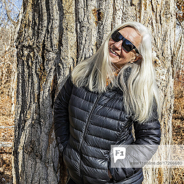 Porträt einer älteren Frau  die vor einem Pappelbaum steht