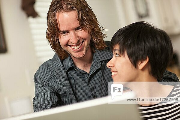 Pretty smiling multiethnic woman and caucasian man using A laptop computer together