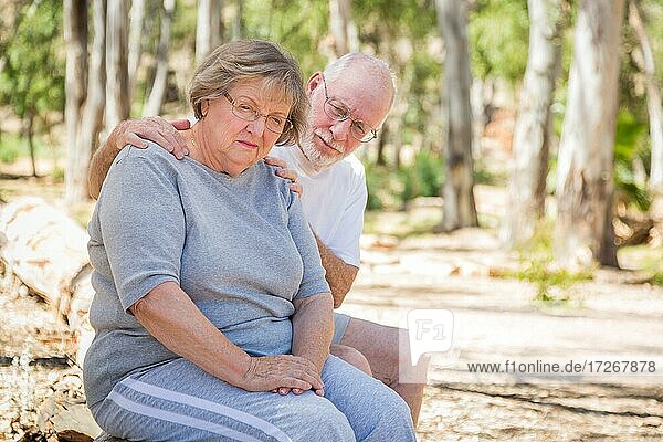 Sehr aufgebrachte Seniorin sitzt mit besorgtem Ehemann im Freien