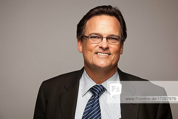 Handsome businessman smiling in suit and tie isolated on a grey background