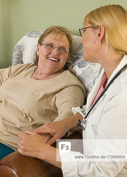 Glücklich lächelnder Arzt oder Krankenschwester im Gespräch mit älterer Frau im Stuhl