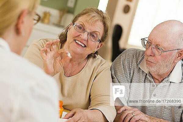 Doctor or nurse explaining prescription medicine to attentive senior couple