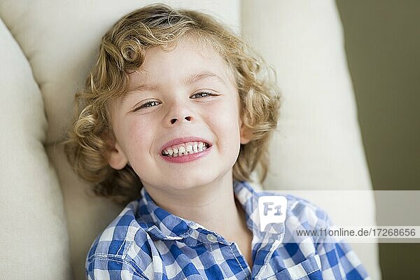 Nette blonde Junge lächelnd für Porträt sitzen im Stuhl