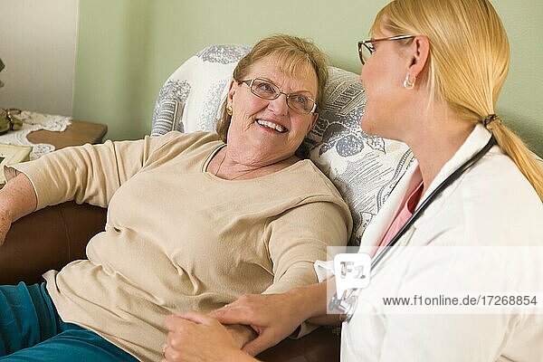 Happy smiling doctor or nurse talking to senior woman in chair