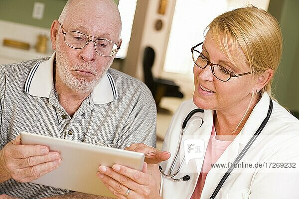 Arzt oder Krankenschwester im Gespräch mit älterem Mann mit Touchpad-Computer