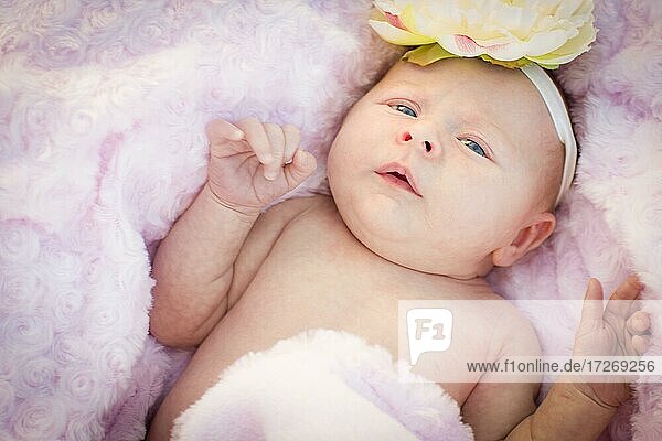 Beautiful newborn baby girl laying peacefully in soft pink blanket