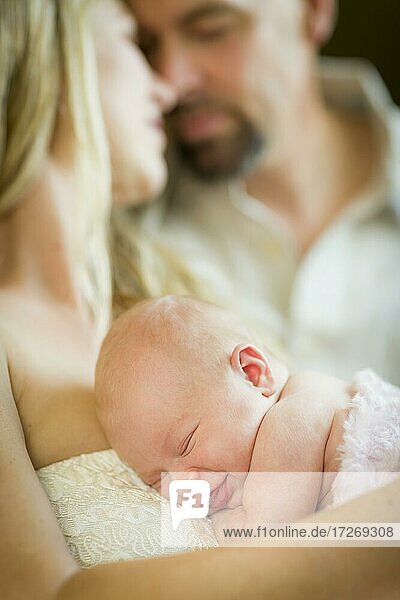 Schönes junges Paar hält ihr neugeborenes schlafendes Baby Mädchen im Inneren
