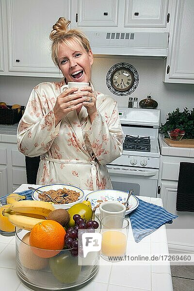 Attractive woman in kitchen with fruit  coffee  orange juice and breakfast bowls