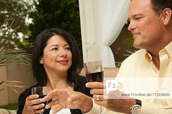 Hispanic woman and caucasian man enjoying wine on the patio