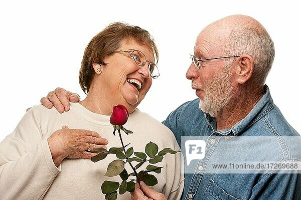 Glücklicher älterer Ehemann gibt rote Rose zu Frau vor weißem Hintergrund