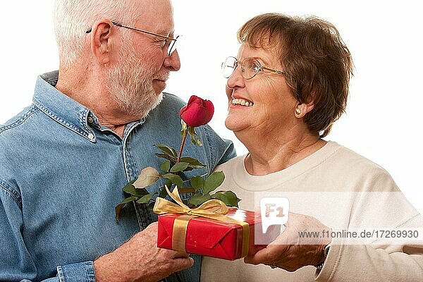 Glückliches älteres Paar mit Geschenk und roter Rose vor einem weißen Hintergrund