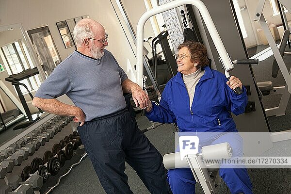 Active senior adult couple working out together in the gym
