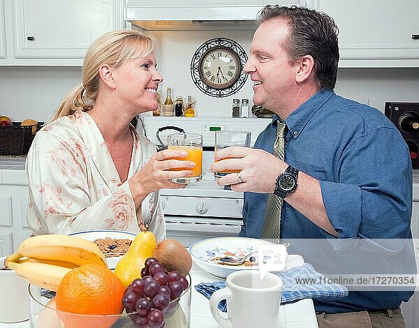 Glückliche attraktive Frau und Geschäftsmann in der Küche mit ihren Orangensaft und Frühstück