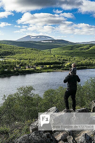 Man with her small baby overlooking the Karasjohka river bordering Norway and Finland  Lapland  Finland  Europe