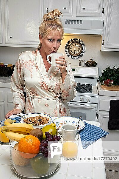 Attraktive Frau in der Küche mit Obst  Kaffee  Orangensaft und Frühstücksschalen