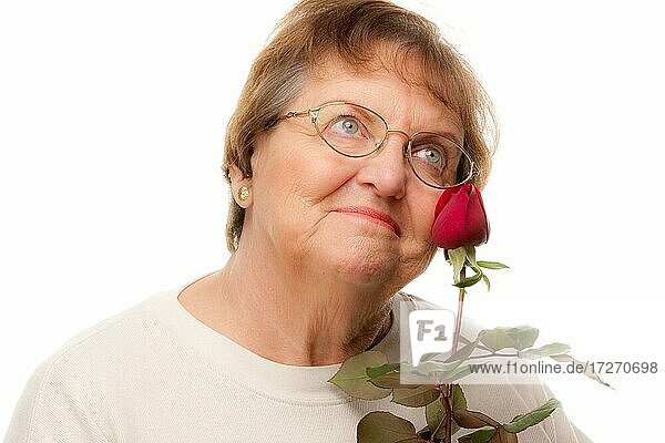 Attraktive ältere Frau mit roter Rose vor einem weißen Hintergrund
