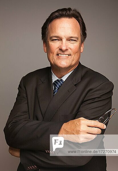 Gutaussehender Geschäftsmann lächelnd in Anzug und Krawatte vor einem grauen Hintergrund