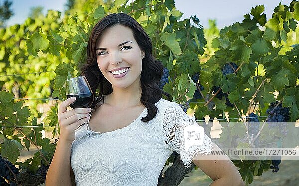 Hübsche gemischtrassige junge erwachsene Frau  die ein Glas Wein im Weinberg genießt