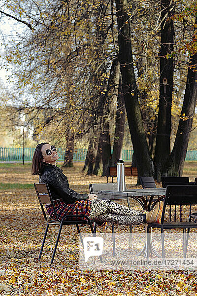 Frau mit Sonnenbrille  die an einem sonnigen Tag im Park sitzt
