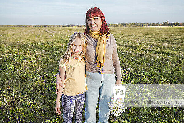 Ältere Frau mit Enkelin auf einem Feld stehend