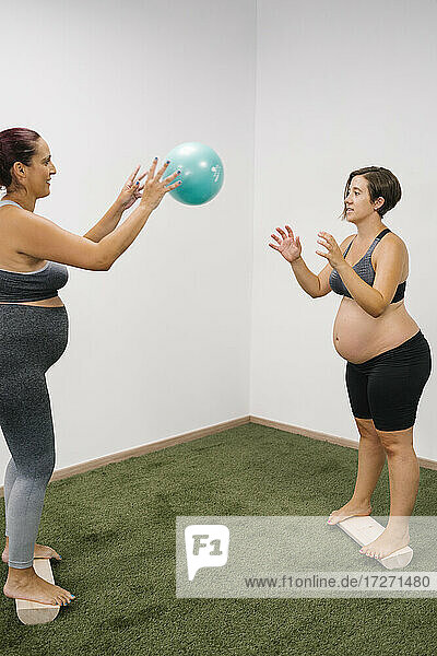 Schwangere Frau  die im Yogastudio mit einem Fitnessball trainiert