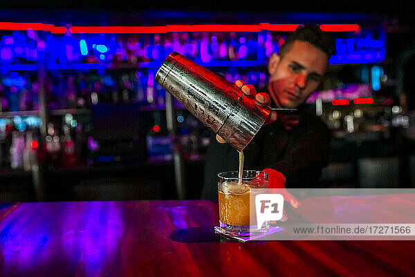 Mittlerer erwachsener Mann  der in einer Bar stehend ein Cocktailgetränk mischt