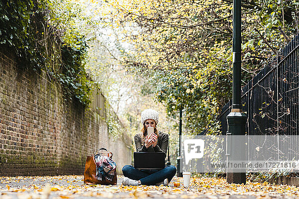 Frau mit Laptop und Smartphone im Sitzen auf der Straße