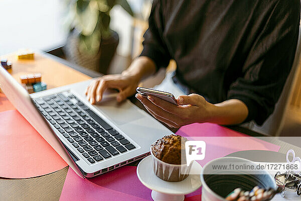 Geschäftsfrau mit Laptop und Smartphone  während sie zu Hause sitzt