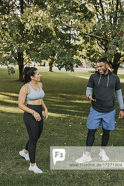 Smiling boyfriend and girlfriend in sports clothing talking while walking at backyard