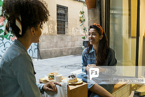 Freunde lächelnd beim Essen und Trinken im Café sitzend
