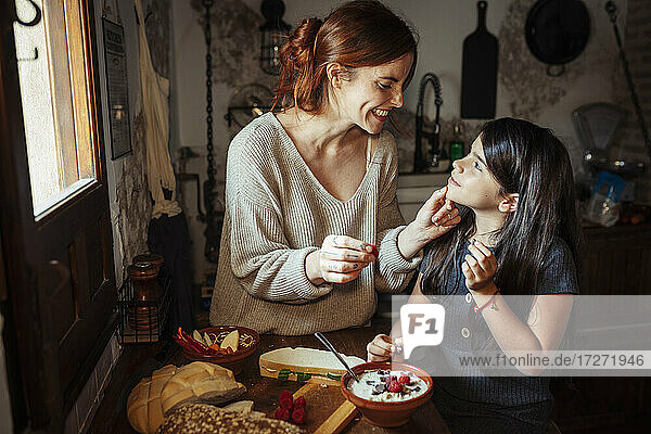 Lächelnde Mutter sieht ihre Tochter an  während sie zu Hause in der Küche steht