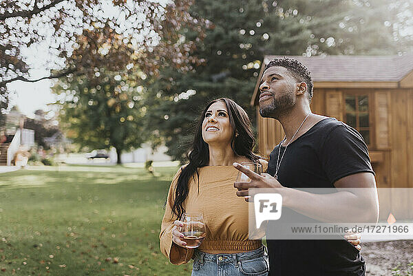 Mann und Frau mit Weinglas  die in einem Hinterhof stehen und nach oben schauen