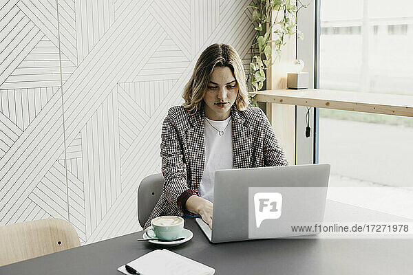 Junge Frau arbeitet am Laptop  während sie in einem Café sitzt