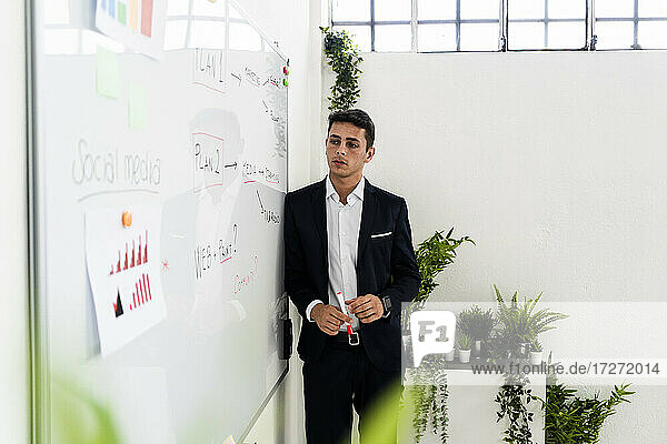 Handsome male professional looking at strategy on whiteboard in office